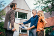© BusinessClass by W61 - Happy real estate agent with couple holding solar panel in front of house