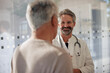 © BusinessClass by W61 - Smiling senior doctor talking to man in hospital