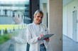 © BusinessClass by W61 - Smiling female doctor with tablet PC and digitized pen leaning on glass window in hospital