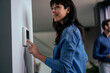 © BusinessClass by W61 - Smiling businesswoman adjusting thermostat with businessman in background