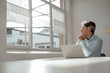 © BusinessClass by W61 - Businessman sitting with laptop looking through window in office