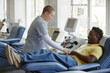 © BusinessClass by W61 - Healthcare worker assisting donor reclining on couch at blood donation center