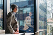 © BusinessClass by W61 - Businessman sitting on desk looking through window in office