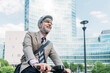 © BusinessClass by W61 - Happy businessman riding electric push scooter in front of office buildings