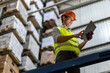 © BusinessClass by W61 - Smiling worker wearing hardhat using tablet PC by railing in warehouse