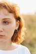© Bohdan - Close-Up of Woman with Red Hair Wearing Silver Earring