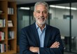 © MstShilpi12 - Confident senior executive with gray hair and beard wearing a suit jacket and blue shirt standing with arms crossed