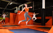 © JackF - Enthusiastic middle-aged woman experiencing thrill of leaping high at vibrant trampoline gym with friends..