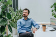 © BusinessClass by W61 - Smiling businessman sitting near plants at desk in office