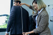 © PINA - woman dressmaker measuring on man back model for new suit clothing collection, fashion stylist designer calculate the design, female freelance tailor working at dress shop small business owner