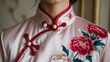 © dang - Elegant crimson qipao collar adorned with pearl buttons and embroidered peonies, set against a muted beige background.
