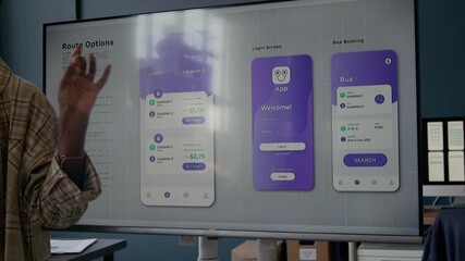 Cropped shot of African American woman presenting interface of bus booking mobile app suggesting clean UI design for welcome and route search pages while pointing at screen in office space
