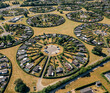 © AmazingAerialAgency - Aerial view of circular garden allotments forming a mesmerizing pattern against the golden fields, a unique urban oasis, BrÃ¸ndby, Denmark.