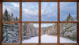 a wooden window frame with six panes offers a view of a snowy landscape featuring pine trees and a cloudy sky