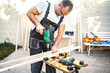 © Jelena - Mature male carpenter using electric drill on a wooden plank outdoors