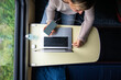 © DimaBerlin - Woman's hands plugging laptop into high-capacity power bank, charging batteries, sitting at table in train compartment, top view. Female remote work while traveling in public transportation.