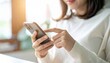 © sakurasaku - A woman's hand operating a smartphone in a bright, sunny room