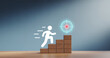 © MSTHUSNEWARA - White stick figure climbing wooden blocks towards glowing target on blue background business growth