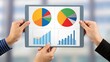 © ng-TDRD - Hands holding a tablet displaying colorful graphs and charts, showcasing data analysis and business insights.