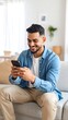 © Abdi - Man using smartphone on couch