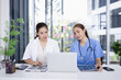 © SOMKID - Female doctor and nurse working together with clipboard and laptop for in modern clinic.