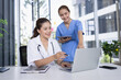 © SOMKID - Female doctor and nurse working together with clipboard and laptop for in modern clinic.