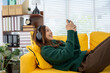 © Kritdanai - Cozy Leisure: Woman Enjoys Digital Time on Sofa