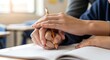 © ALLmost - Close-up of hands guiding a child's hand holding a pencil, writing on paper at a desk, likely in a classroom setting.
