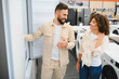 © Serhii - Couple choosing refrigerator in electronics store discussing purchase