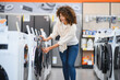 © Serhii - Woman choosing washing machine in electronics store