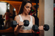 © Ljustina - Determined sportswoman lifting dumbbells in gym fitness workout