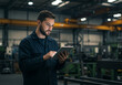 © Madiha - A man in a factory looks at a tablet in his hands with machinery in the background of the image
