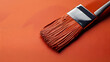 © Aliaksandr - Paintbrush loaded with orange paint on a matching orange surface. Painting and home improvement concept.