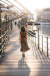 © Doralin - Woman walking away on the bridge in genoa at sunset