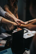 © qunica.com - A group of people in an office environment unite hands above a desk, symbolizing teamwork and collaboration.