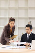 © SOMKID - Two Asian business people with analyzing financial report working together in office.