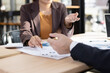 © SOMKID - Asian businesswoman and businessman are holding paper documents financial analysis data charts in office working space.