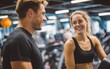 © Korkiat - A man and woman in their early thirties, smiling at each other as they stand on the treadmill together in an indoor gym setting.