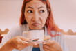 © EdNurg - woman grimacing while sipping a cup of unpleasant coffee in a cafe, displaying clear signs of disgust and disappointment