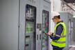 © JD Studio - Power station engineer inspect control panel with clipboard in industrial facility checking system status for safety and maintenance work with protective helmet and reflective vest