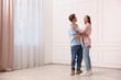 © New Africa - Happy couple dancing together near white wall at home. Space for text