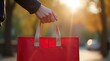 © Alex Pios - Wide shot of a hand grabbing a red insulated food delivery bag outside, bright natural light, showing action of picking up food order ready for delivery.