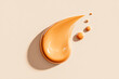 © Lilufa - A smear of beige foundation makeup is displayed with small drops on a neutral background