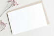 © KidSpace - Blank postcard mockup with envelope on beige background with gypsophila flowers.