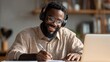 © Johannes - Young happy smiling African American adult student wearing headphones having virtual education class meeting online call e learning webinar on laptop at home office writing notes., no logos, no brand
