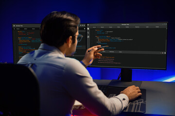 Working smart IT developer pointing data software development on two pc screen, creating application program updated version online website page system online at neon light cyber office. Surmise.