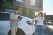 © Serhii - Couple charging electric car at home using green energy