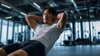© bephoto - 男性がジムでトレーニングし腹筋を鍛える様子