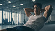 © bephoto - 男性がジムでトレーニングし腹筋を鍛える様子