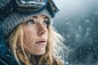 © Oleh - Female snowboarder with snow goggles and a beanie looks upward during a light snowfall, her face and hair dusted with snowflakes, creating a serene winter scene